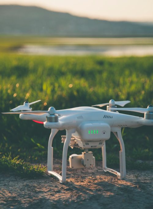 pexels-photo-997131-997131 A white drone rests on a grass field during a summer sunset, showcasing technology in nature.